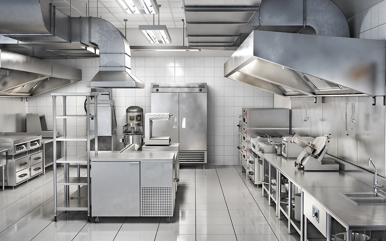 Eine Großküche mit Geräten aus Edelstahl, darunter Backöfen, Kühlschränke, ein Mixer, Vorbereitungstische, Regale und industrielle Lüftungshauben.